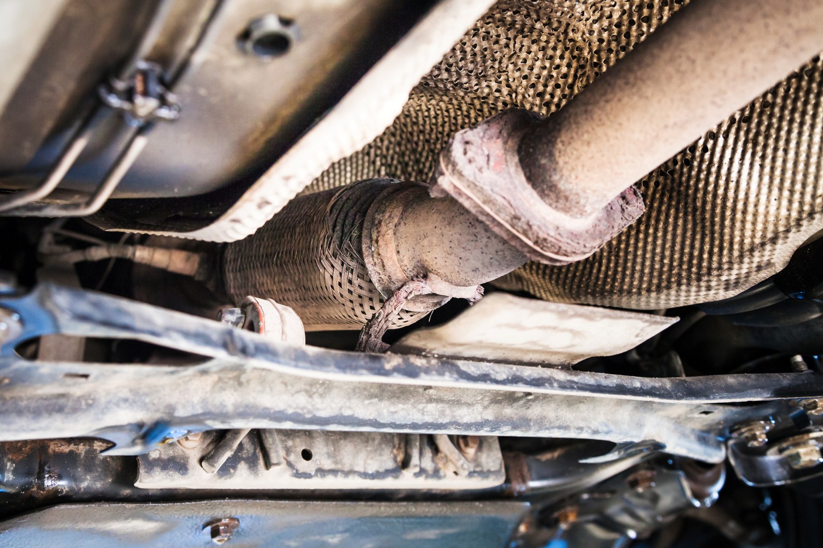 repairing of corrugation muffler of exhaust system in car workshop - bottom view of old broken corrugation muffler on car